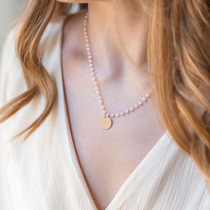 Close-up of a woman wearing a delicate necklace with small pearls and a gold pendant.